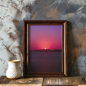 Purple sunset sky wall art in a thick wooden frame, laying against an artistic wall with some traces of paint