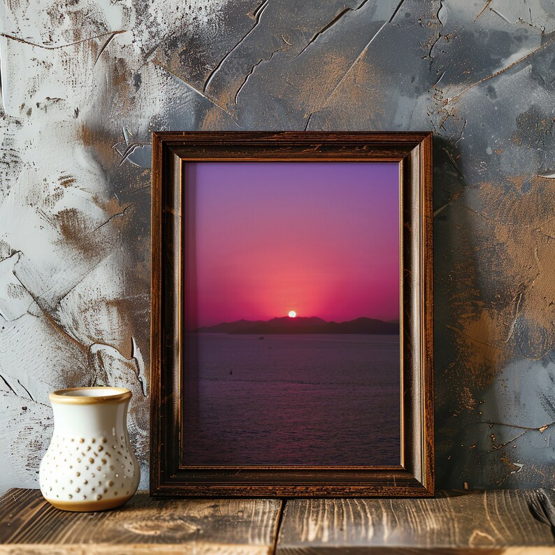 Purple sunset sky wall art in a thick wooden frame, laying against an artistic wall with some traces of paint