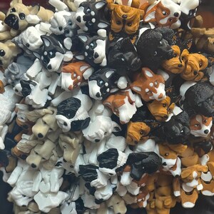 Pode incluir: Uma grande coleção de pequenas figuras de cães de plástico coloridas. Os cães estão em várias poses e raças, incluindo um bulldog, um dachshund, um husky e um chihuahua.