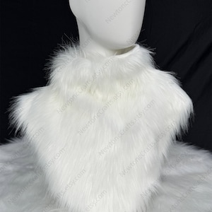 Può includere: Un soffice colletto in finta pelliccia bianca, esposto su una testa di manichino. Il colletto è un accessorio morbido e strutturato, perfetto per aggiungere un tocco di eleganza. Lo sfondo è di un colore scuro e uniforme, che mette in risalto il colore bianco brillante del colletto.