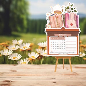 May include: A January calendar on a wooden easel featuring an illustration of books, a teapot, and a sealed envelope. The calendar grid displays dates from 1 to 31 and includes the quote: "Isn't it nice to think that tomorrow is a new day with no mistakes in it yet?"&mdash;Anne of Green Gables.