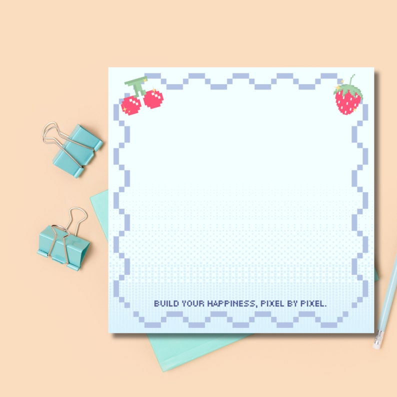 Puede incluir: Un bloc de notas pixelado azul y blanco con un dise&ntilde;o de cereza y fresa. El bloc de notas tiene un borde ondulado y el texto "BUILD YOUR HAPPINESS, PIXEL BY PIXEL." en la parte inferior.