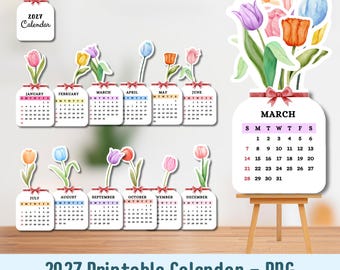 May include: A 2027 printable calendar set featuring twelve individual monthly cards shaped like mason jars, each topped with watercolour-style tulips in various colours. A larger March calendar card is displayed on a small wooden easel.