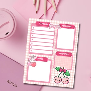 May include: A pink and white checkered notepad with sections for a to-do list, reminders, notes, and priorities. Adorned with a bow and cherry illustrations, the notepad is surrounded by pink stationery.