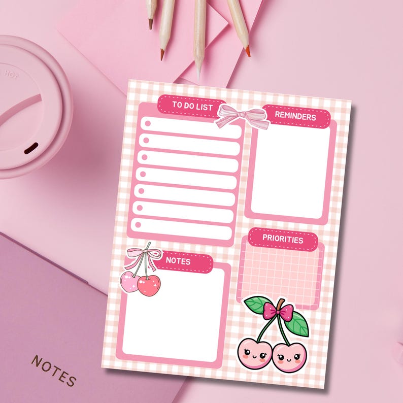May include: A pink and white checkered notepad with sections for a to-do list, reminders, notes, and priorities. Adorned with a bow and cherry illustrations, the notepad is surrounded by pink stationery.