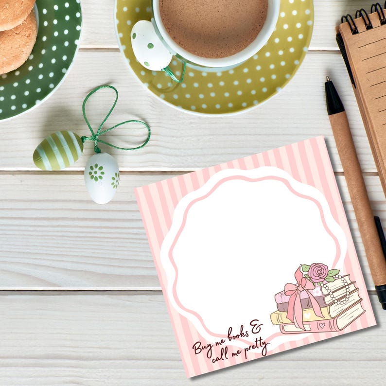 K&ouml;nnte beinhalten: Draufsicht auf einen rosa-wei&szlig; gestreiften Notizblock mit dekorativem Rand und dem Text "Buy me books & call me pretty." Ein Stapel B&uuml;cher mit Schleife und Perlen befindet sich in der Ecke. Eine Tasse Kaffee, Kekse und dekorative Eier sind ebenfalls vorhanden.