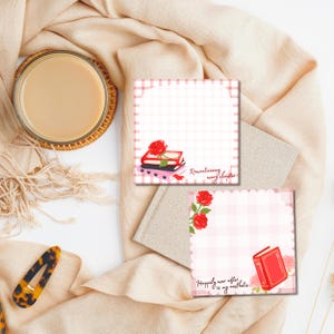 K&ouml;nnte beinhalten: Zwei quadratische Notizbl&ouml;cke mit rosa Vichy-Muster, roten Rosen und Buchillustrationen. Auf einem Notizblock steht "Romanticizing every chapter", auf dem anderen "Happily ever after is my aesthetic."
