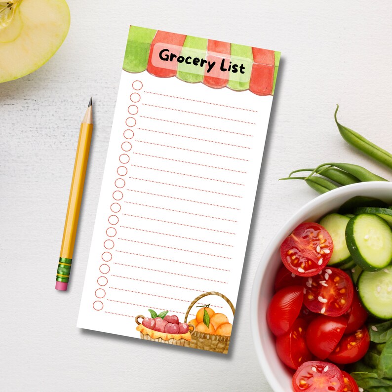 May include: A grocery list notepad with a red and green awning design. The notepad has a white background with red lines and a section at the bottom with a basket of fruit.