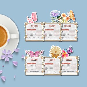 Op de afbeelding: Een set van zes 2026 kalenderstickers, elk met een maand van juli tot en met december. De stickers zijn versierd met bloemen- en vlindermotieven. De kalender staat op een lichte achtergrond met een blauwe achtergrond.