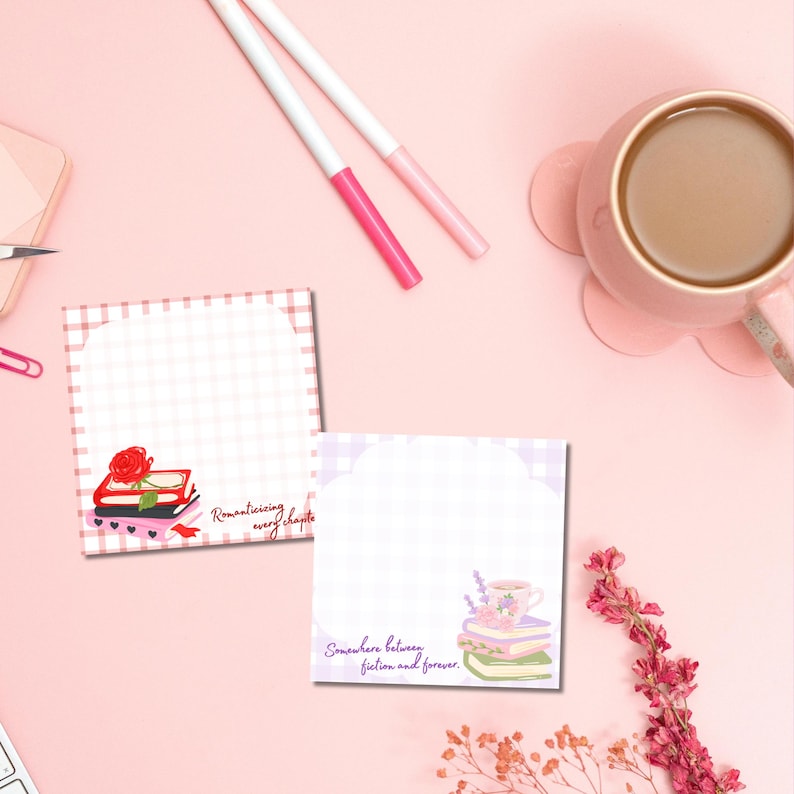 K&ouml;nnte beinhalten: Zwei quadratische Notizbl&ouml;cke mit Vichy-Muster und Illustrationen von B&uuml;chern, Rosen und Teetassen. Auf einem Notizblock steht "Romanticising every chapter", auf dem anderen "Somewhere between fiction and forever". Rosa Stifte und eine Tasse Kaffee sind ebenfalls zu sehen.