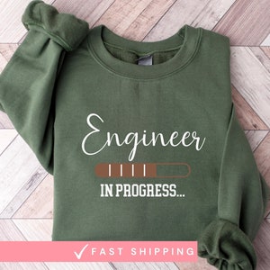 May include: A green sweatshirt with the text "Engineer in progress..." printed on the front. The text is in a white font with a brown progress bar.