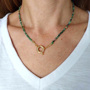 Op de afbeelding: Een delicate gouden ketting met groene en zwarte edelsteen kralen. De ketting heeft een gouden toggle sluiting.
