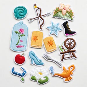 Puede incluir: Parches bordados con diseños de cuentos de hadas. Incluye una rosa en una campana de cristal, un arco y flecha, un copo de nieve, un zapato de cristal, una manzana roja y una lámpara mágica. Cada parche tiene un borde blanco.