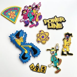Könnte beinhalten: Eine Sammlung von aufgestickten Aufnähern mit Zeichentrickfiguren und Designs. Die Aufnäher enthalten die Worte "Power Line" und die Zahlen "95". Die Farbpalette umfasst Gelb, Blau, Rosa und Schwarz.
