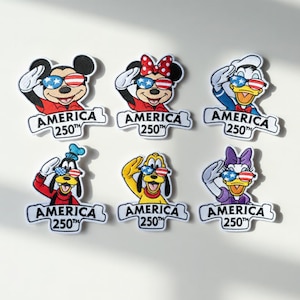 以下が含まれることがあります： ディズニーのキャラクターが敬礼し、アメリカ国旗のデザインのサングラスをかけている刺繍ワッペン6枚。各ワッペンには、白いバナーに「AMERICA 250TH」の文字が入っています。