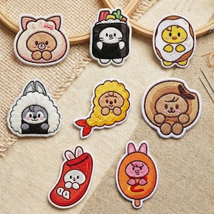 May include: A selection of embroidered patches with adorable cartoon characters. Designs include a bear in a bear costume, a sushi roll with a cat face, a chick in an egg, a bunny, a shrimp, a dog in a circle, a chili pepper with a bunny, and a pig on a popsicle.