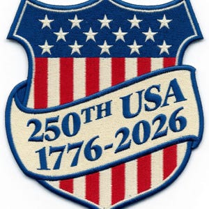 Puede incluir: Parche bordado en forma de escudo, con el diseño de la bandera estadounidense con rayas rojas y blancas y una parte superior azul con estrellas blancas. Una pancarta muestra "250th USA 1776-2026" en azul.