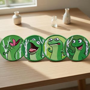 Pode incluir: Quatro patches redondos verdes com sapos de desenho animado. Cada patch apresenta uma expressão de sapo diferente, em um fundo de bétulas brancas. Os patches estão em uma superfície de madeira marrom clara.