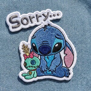 May include: Embroidered patch featuring the character Stitch from Lilo & Stitch, in shades of blue, with a sad expression. A small green doll with a pink bow is next to Stitch. The word "Sorry..." is embroidered above.