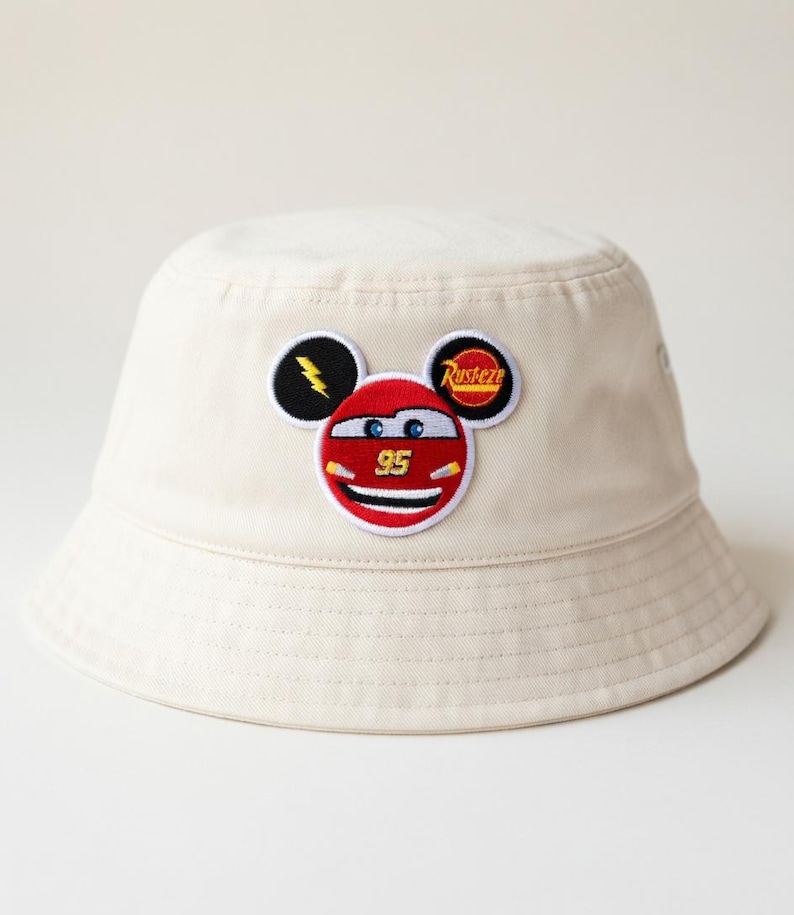 Puede incluir: Un juego de tres tazas de cer&aacute;mica con un esmalte moteado de color crema. Cada taza presenta un dise&ntilde;o pintado a mano diferente: una hoja azul y verde, una flor amarilla y una baya roja. Las tazas tienen una forma simple y redondeada.