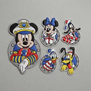 May include: Set of six embroidered patches featuring Disney characters Mickey Mouse, Minnie Mouse, Goofy, Donald Duck, and Pluto. Each patch has a nautical theme with vibrant colors and detailed stitching. Perfect for decorating clothing or accessories.