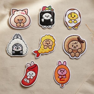 May include: A collection of embroidered patches featuring cute cartoon characters in various food-themed costumes. Designs include a bear in a bunny outfit, a sushi cat, a chick in an egg, a bunny in a cloud, a shrimp, a lion, a bunny in a sock, and a popsicle.