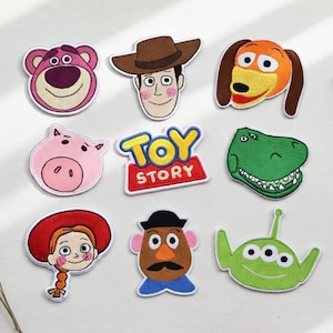 May include: A collection of embroidered patches featuring characters from the animated film "Toy Story." The patches include Lotso, Woody, Slinky Dog, Hamm, Rex, Jessie, Mr. Potato Head, the Little Green Men, and the "Toy Story" logo.