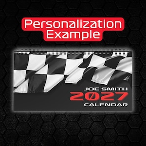 May include: A spiral-bound wall calendar featuring a black and white chequered flag graphic at the top. The text reads Personalization Example, Joe Smith, 2027, and Calendar. The design uses a black background with bold red lettering for the year.