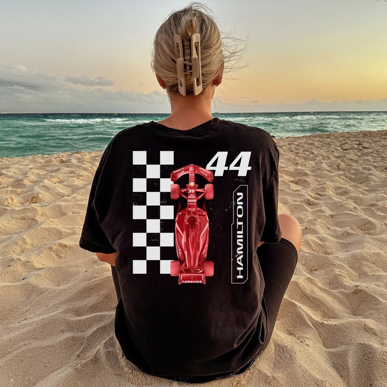 K&ouml;nnte beinhalten: Schwarzes T-Shirt mit einem wei&szlig;en Karomuster, einem roten Rennwagen und dem Text "44 HAMILTON".