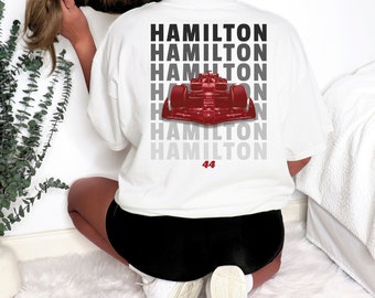 May include: White t-shirt with a red race car graphic and the text "HAMILTON" repeated five times, with the number "44" below the last word.