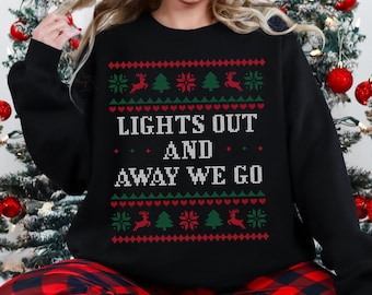 May include: Black Christmas sweater with a red and green pattern and the text "Lights Out And Away We Go".