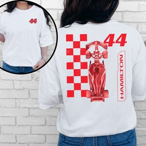 K&ouml;nnte beinhalten: Wei&szlig;es T-Shirt mit rotem Karomuster, einem roten Rennwagen und der Nummer "44" sowie dem Wort "HAMILTON" auf der R&uuml;ckseite.