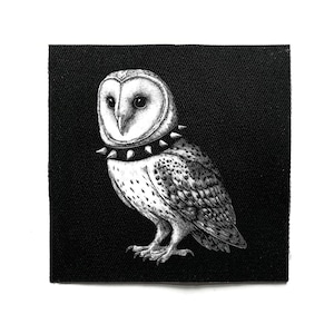 May include: A black and white patch showing a detailed illustration of a barn owl wearing a studded collar. The owl is rendered in a realistic style, with intricate feather details and a focused gaze. The patch is square-shaped and set against a black background.