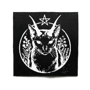 Könnte beinhalten: Schwarzer quadratischer Aufnäher mit einer weißen Illustration einer Katze mit Hörnern, einem Pentagramm und floralen Elementen in einem Kreis. Die Katze hat leuchtende Augen und einen ernsten Ausdruck. Für Kleidung oder Accessoires.