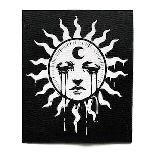 May include: Black and white patch featuring a sun face with a crescent moon above the forehead. The sun has stylized rays and tears streaming down from the eyes. The design is on a black background.