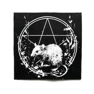 Peut inclure: Écusson carré noir avec une illustration blanche d'un rat à l'intérieur d'un pentagramme et d'éléments floraux. Le rat est détaillé avec des ombres, le design est sur fond noir.