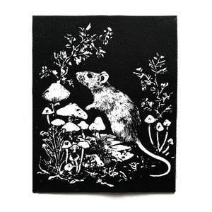 May include: Black and white patch featuring a detailed illustration of a rat amidst mushrooms and foliage. The design is a nature-themed graphic, perfect for adding to clothing or accessories.