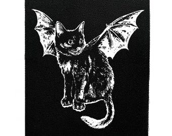 May include: Black and white patch featuring a cat with bat wings. The cat is sitting upright with its tail curled. The wings are spread out behind the cat. The patch is on a black background.