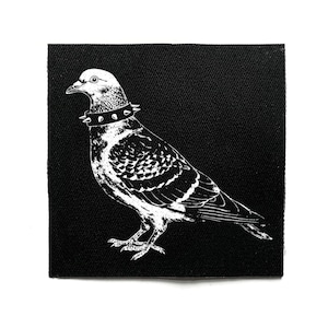 Könnte beinhalten: Schwarz-weißer Aufnäher mit einer Taube, die einen Nietenhalsband trägt. Der Vogel ist detailliert dargestellt, vor einem einfarbigen schwarzen Hintergrund. Der Aufnäher ist quadratisch.