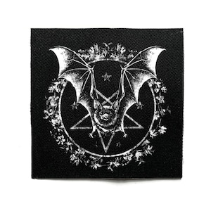 Op de afbeelding: Zwart vierkantige patch met een witte illustratie van een vleermuis met uitgespreide vleugels, een ster en een pentagram. De vleermuis is omcirkeld door een bloemenkrans. Het ontwerp is gedetailleerd en in gotische stijl.