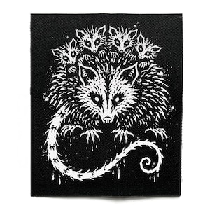 Könnte beinhalten: Ein rechteckiger schwarzer Stoffaufnäher mit einem weißen Siebdruckmotiv, das ein großes Opossum mit vier kleineren Opossums auf dem Rücken zeigt. Das Design verwendet kontrastreiche Tinte, um die Fellstruktur und den Schwanz darzustellen.