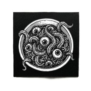 Może przedstawiać: Czarno-biała naszywka przedstawiająca miskę spaghetti z wieloma gałkami ocznymi i mackami. Ilustracja jest szczegółowa i ma gotycki lub horror motyw. Naszywka jest kwadratowa i ma czarne tło.
