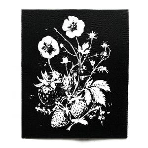 Könnte beinhalten: Schwarzer quadratischer Aufnäher mit weißem Blumendesign. Das Design zeigt Erdbeeren, Blumen, Blätter und Stiele und erzeugt eine detaillierte Illustration. Der Aufnäher ist wahrscheinlich für Kleidung oder Accessoires.