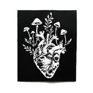 Peut inclure: Écusson carré noir avec une illustration blanche d'un cœur humain, de champignons et de feuillage. Le dessin est détaillé et réalisé en style linework. Idéal pour les vêtements ou accessoires.