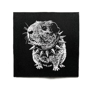 May include: Square black and white patch showing a guinea pig wearing a studded collar. The illustration style highlights the texture of the guinea pig's fur and the collar's spikes. The patch is designed for application.