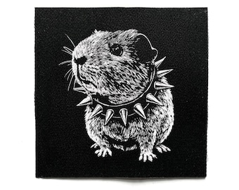 May include: Black and white patch featuring a guinea pig wearing a studded collar. The guinea pig is depicted in a detailed, illustrative style, with a focus on texture and expression. The patch is square-shaped.