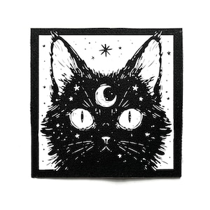 Peut inclure: Écusson noir et blanc représentant un chat stylisé avec de grands yeux, un croissant de lune entre les oreilles et des étoiles. Le pelage du chat est détaillé avec de minuscules points blancs, créant un effet de nuit étoilée. L'écusson a une bordure noire.