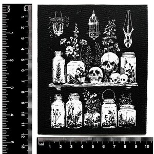 Puede incluir: Parche en blanco y negro con un dise&ntilde;o bot&aacute;nico y g&oacute;tico. Muestra tarros, calaveras y plantas colgantes. El dise&ntilde;o incluye una estanter&iacute;a detallada y arreglos florales. El parche mide aproximadamente 10 cm por 10 cm.
