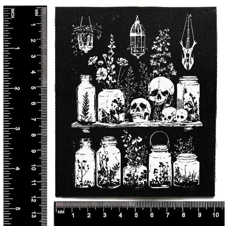 Puede incluir: Parche en blanco y negro con un dise&ntilde;o bot&aacute;nico y g&oacute;tico. Muestra tarros, calaveras y plantas colgantes. El dise&ntilde;o incluye una estanter&iacute;a detallada y arreglos florales. El parche mide aproximadamente 10 cm por 10 cm.