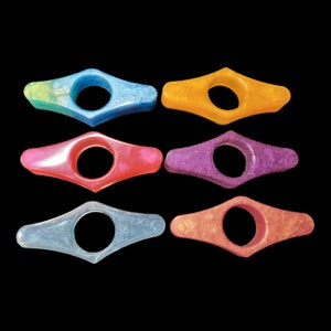 May include: Six colorful bookends in various shades of blue, pink, purple, orange, and yellow. Each bookend is shaped like a teardrop with a rounded hole in the center.